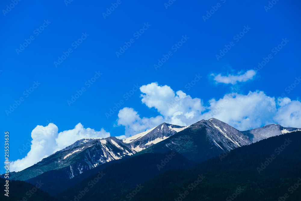 Beautiful alpine ice mountains peaks with snow, summer time, blue sky background.
