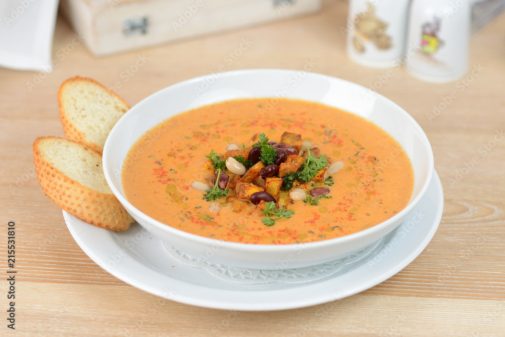pumpkin soup with beans and croutons on a white plate pumpkin soup with beans and croutons on a white plate