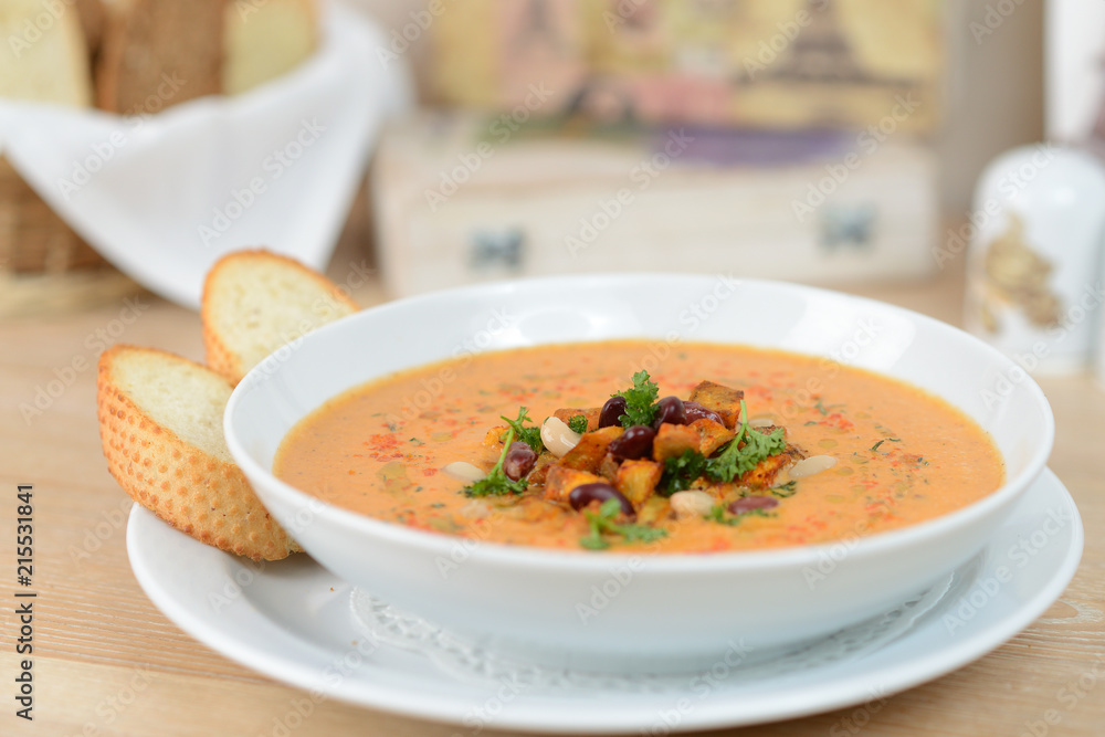 pumpkin soup with beans and croutons on a white plate pumpkin soup with beans and croutons on a white plate