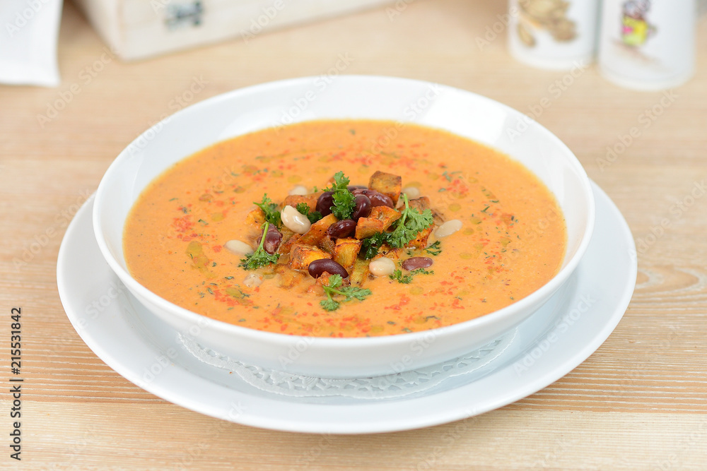 pumpkin soup with beans and croutons on a white plate pumpkin soup with beans and croutons on a white plate