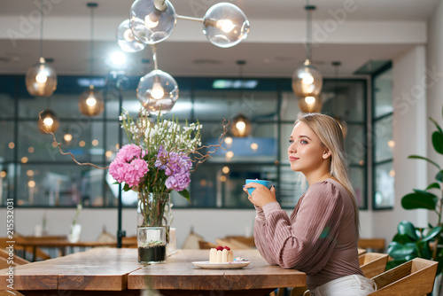 Beatiful girl drinking coffee in local cafe with wooden interior. photo