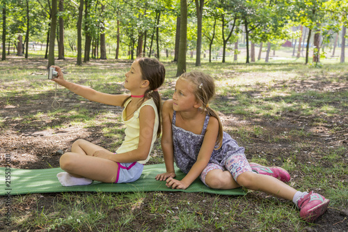 Two girls taking a photo in the park. The girls in the park make selfies. two beautifu teenager girls make selfie in the park.