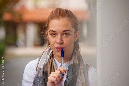 Portrait of a cute girl student studying after class outdoors against a background of blurry buildings