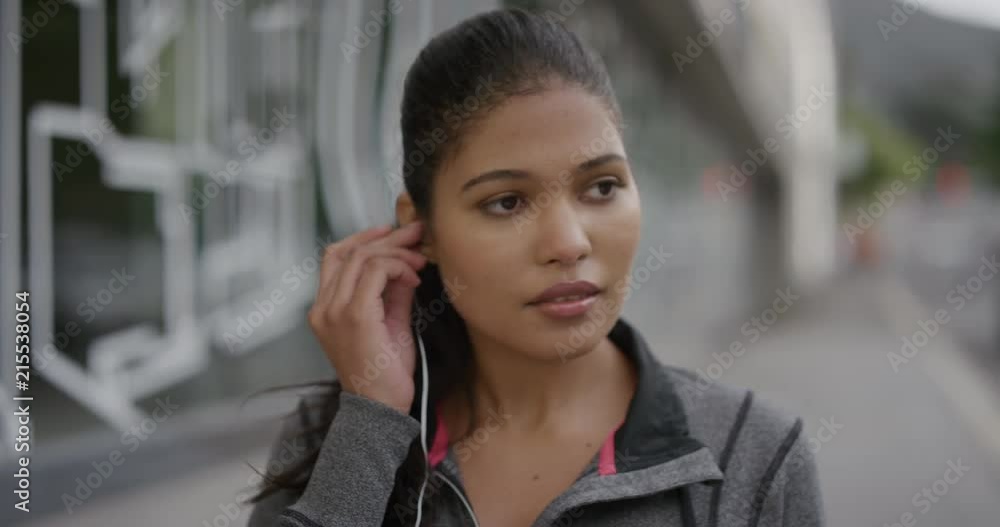 portrait of young woman puts on earphones looking at camera enjoying listening to music in urban city street real people series portrait of young woman puts on earphones looking at camera enjoying listening to music in urban city street real people series
