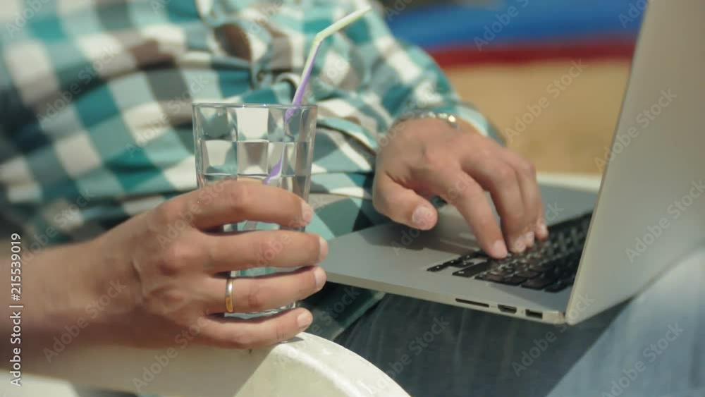 A young girl in a white bikini lies and tans on a deckchair on a sea sandy beach and is working on a laptop A young girl in a white bikini lies and tans on a deckchair on a sea sandy beach and is working on a laptop