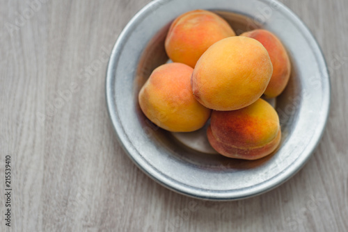 Still life of peaches in a rustic plate on a wooden background