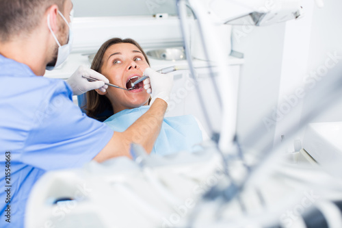 Dentist is treating patient which is sitting in dental chair in clinic