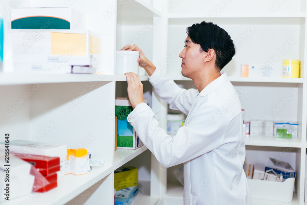 Asian pharmacist doctor in white gown checking medical health stock products and working in drugstore in shop. Asian pharmacist doctor in white gown checking medical health stock products and working in drugstore in shop.