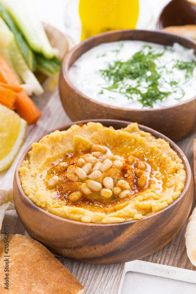 hummus in wooden bowl with pita bread and fresh vegetables, vertical hummus in wooden bowl with pita bread and fresh vegetables, vertical