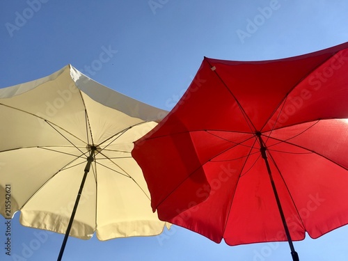 Sonnenschirm in rot und weiss vor blauem Himmel im Sommer 