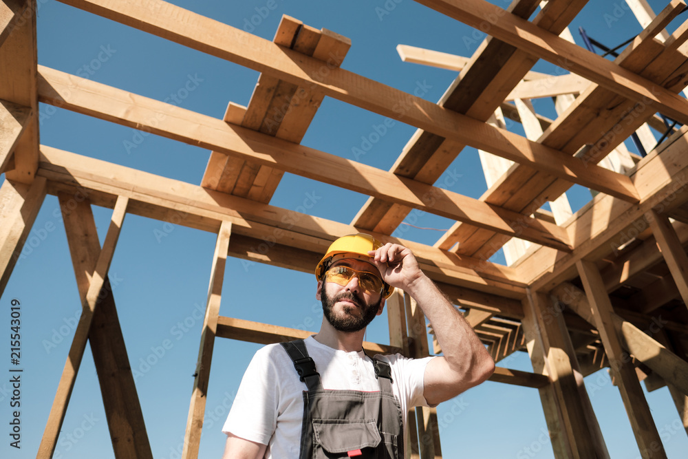 The man is a builder on the roof of a wooden frame house. The man is a builder on the roof of a wooden frame house.