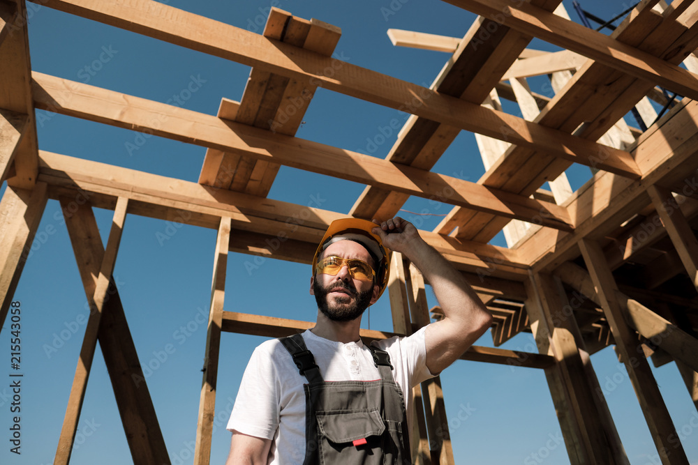 The man is a builder on the roof of a wooden frame house. The man is a builder on the roof of a wooden frame house.