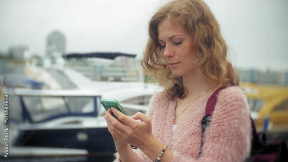 A girl using a smartphone at seaside,yacht and sailing in the harbour. A girl using a smartphone at seaside,yacht and sailing in the harbour.