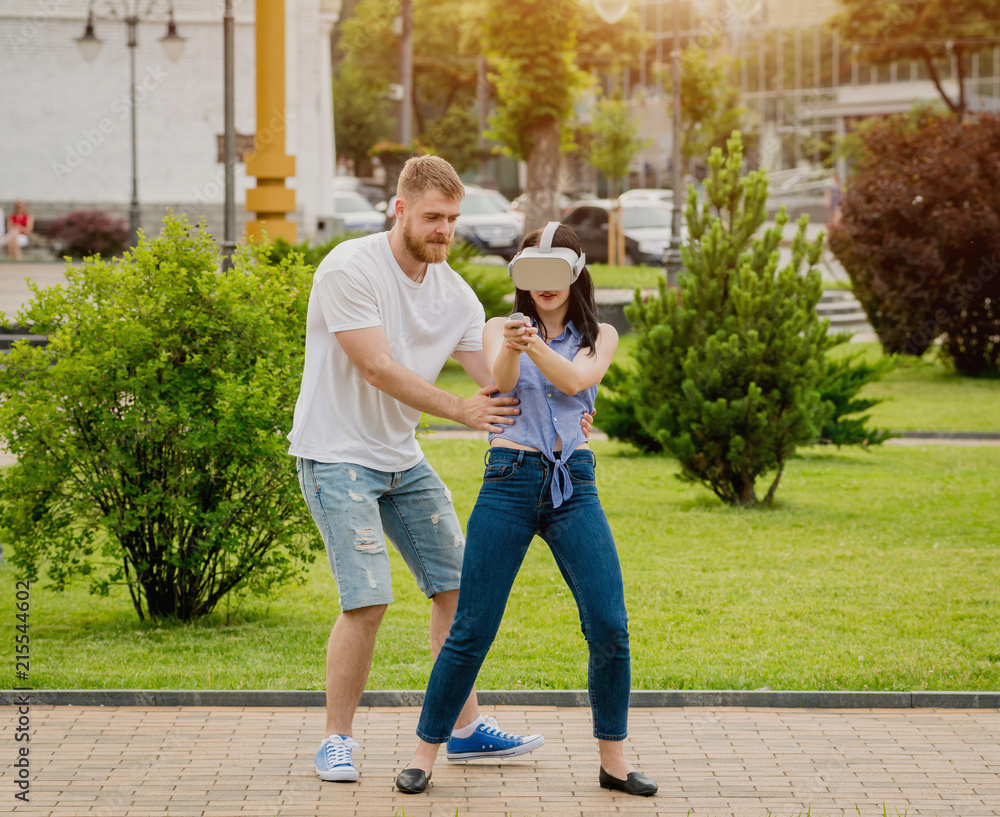A young couple plays a game using virtual reality glasses on the street.