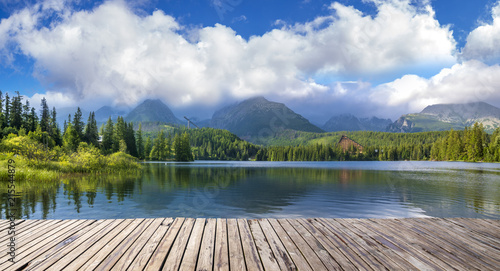 Wooden path on alpine lake Strbske Pleso with reflection of mountains, sky and clouds in the calm water, High Tatras, Slovakia © Mike Mareen