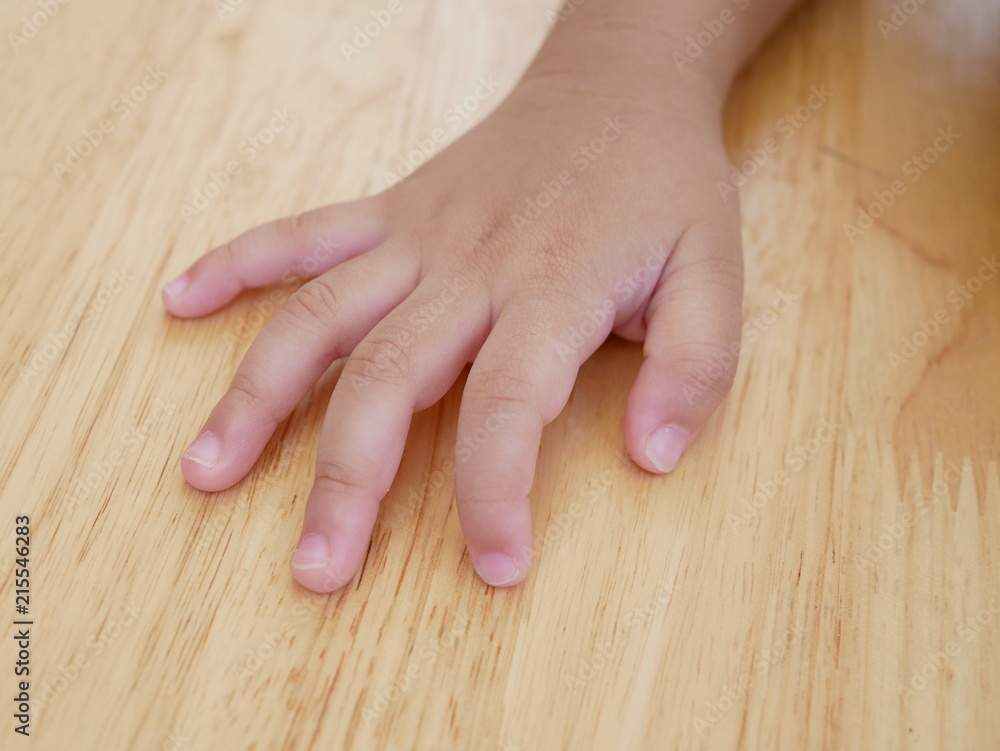 Little Asian baby girl's hand, 31 months old, placed on a wooden table Little Asian baby girl's hand, 31 months old, placed on a wooden table