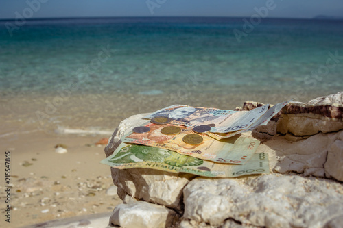 Albanian coins and banknotes on the beach.