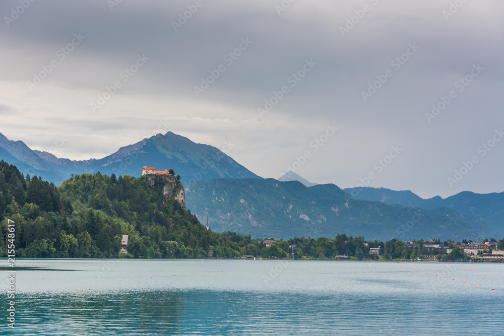 Bled castle after the storm. Dark grey sky with clouds above the Bled lake.