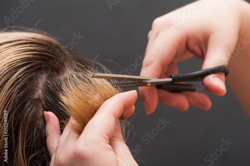 Trimming blond hair with scissors