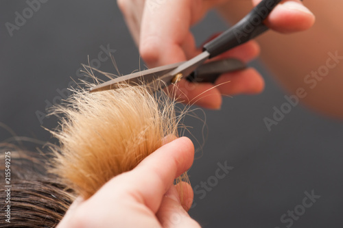 Trimming blond hair with scissor