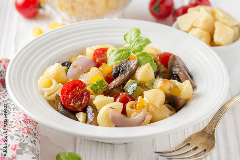 Italian pasta with fried vegetables and mushrooms, zucchini, cherry tomatoes, champignon, cheese and Basil. White plate Italian pasta with fried vegetables and mushrooms, zucchini, cherry tomatoes, champignon, cheese and Basil. White plate