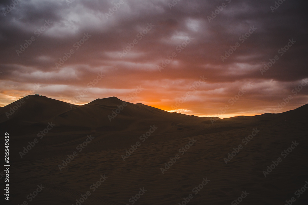 Sand dunes of the desert in Huacachina, near Ica, Peru at a cloudy sunset