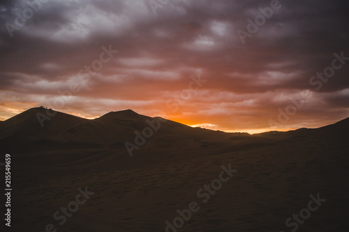 Sand dunes of the desert in Huacachina, near Ica, Peru at a cloudy sunset