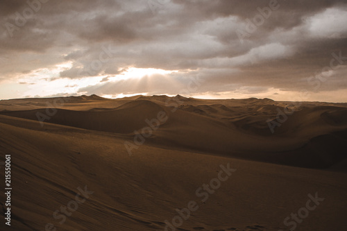 Sand dunes of the desert in Huacachina, near Ica, Peru at a cloudy sunset