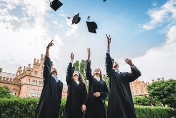 We've finally graduated!Graduates near university are throwing up hats in the air.