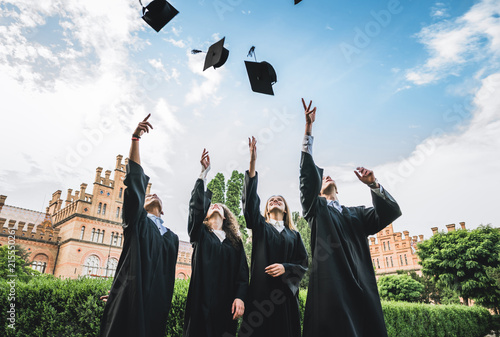 We've finally graduated!Graduates near university are throwing up hats in the air.
