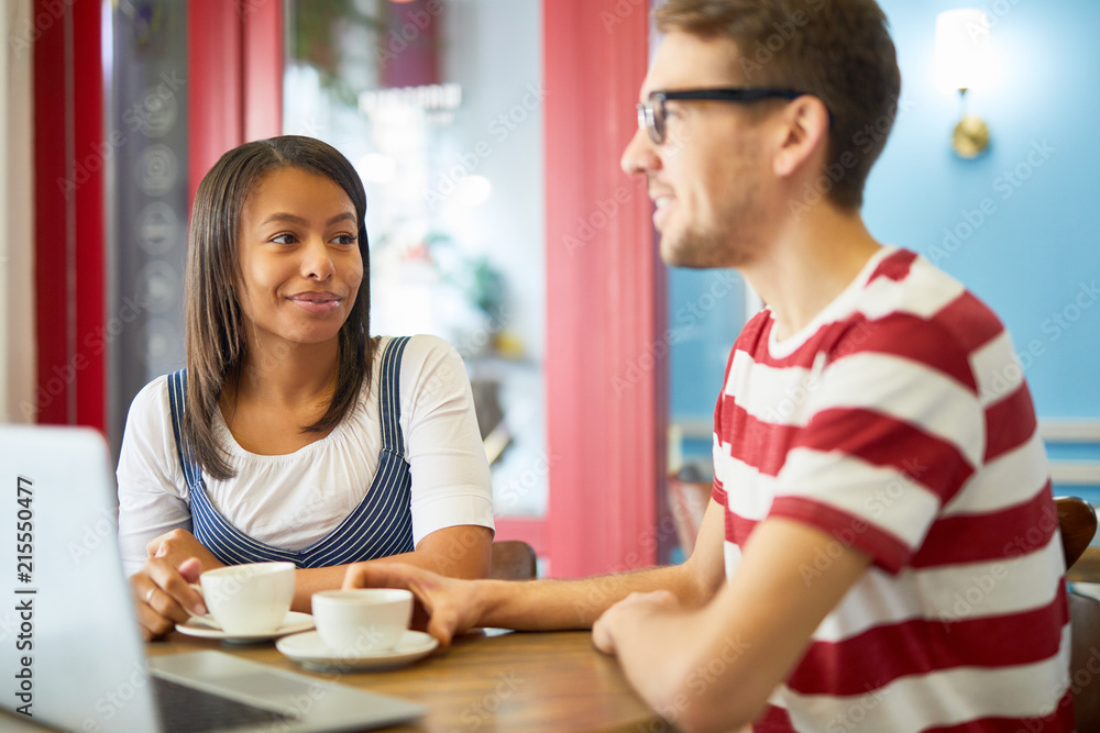 Young businesswoman and businessman in casualwear spending coffee-break in cafe Young businesswoman and businessman in casualwear spending coffee-break in cafe