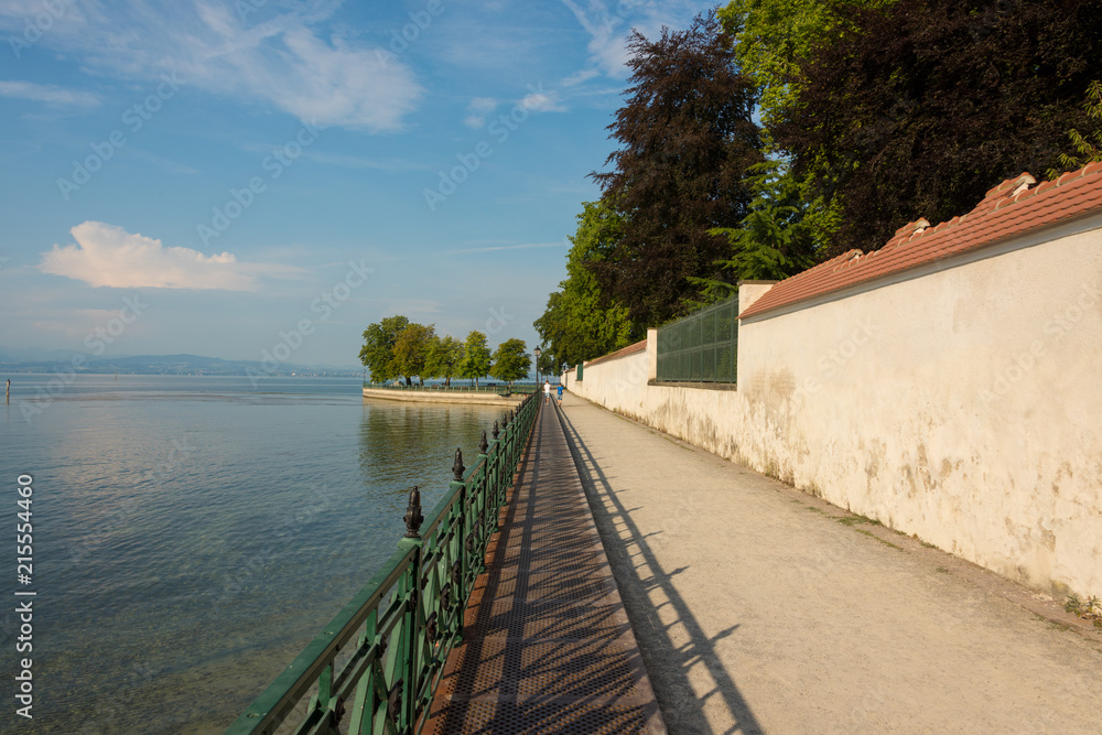 Footpath with old iron railing along the castle wall in the park at Lake Constance in Friedrichshafen