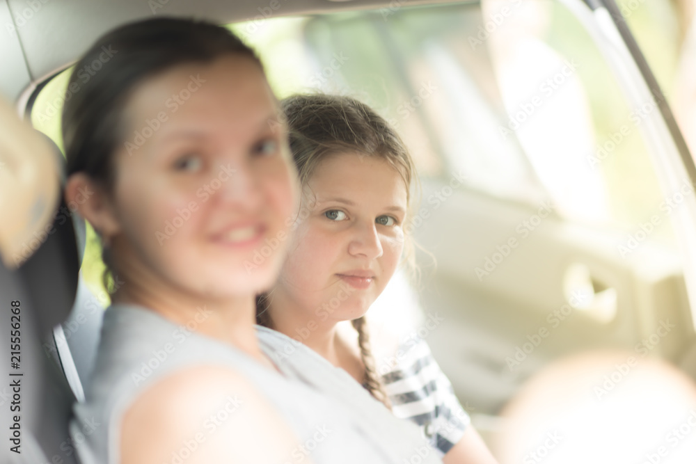 Mother and daughter sit together in car back seat at the sunny day Mother and daughter sit together in car back seat at the sunny day