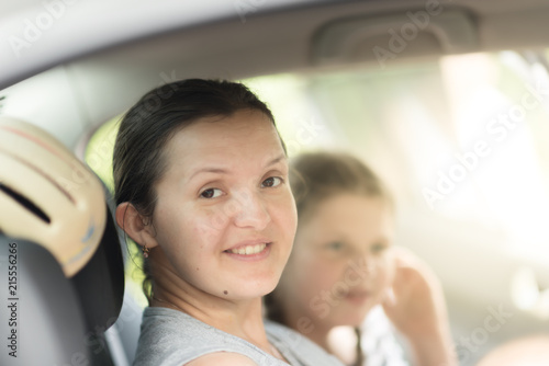 Mother and daughter sit together in car back seat at the sunny day © Mak