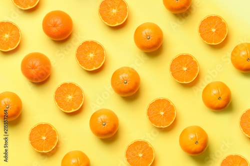 Fruit pattern of fresh orange slices on yellow background. Top view. Copy Space. Pop art design, creative summer concept. Half of citrus in minimal flat lay style.