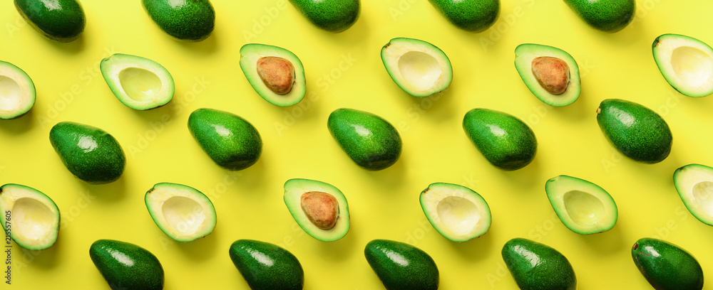 Fototapeta Avocado pattern on yellow background. Top view. Banner. Pop art design, creative summer food concept. Green avocadoes, minimal flat lay style. Banner