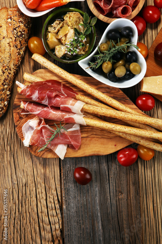 Zestaw włoskich przekąsek do antipasti. Odmiana sera, śródziemnomorskie oliwki, crudo, prosciutto di parma, salami i wino w kieliszkach na drewnianym tle grunge.