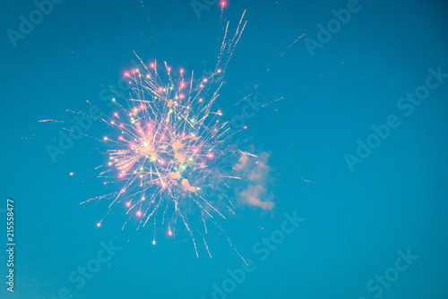 Celebratory fireworks against blue sky.