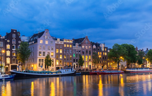 Night city view of Amsterdam canal, typical dutch houses and boats, Holland, Netherlands.