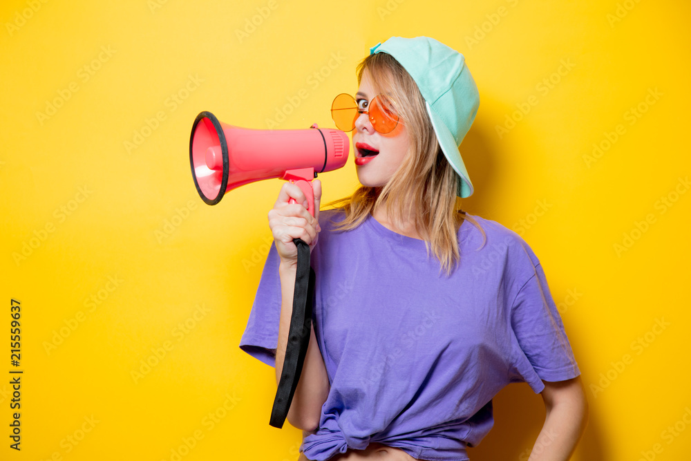 Young style girl in purple clothes with pink megaphone on yellow background. Symbolizes female resistance. Clothes in 1980s style Young style girl in purple clothes with pink megaphone on yellow background. Symbolizes female resistance. Clothes in 1980s style