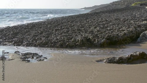 waves breaking in abeach agaisnt a rock photo