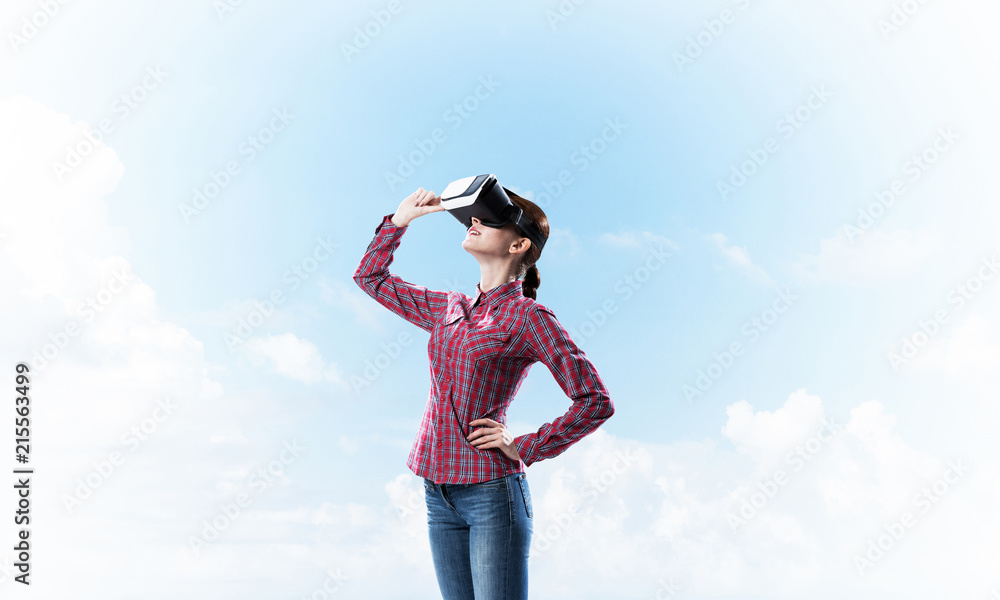 Girl in checked shirt wearing VR glasses experiencing another re Girl in checked shirt wearing VR glasses experiencing another re