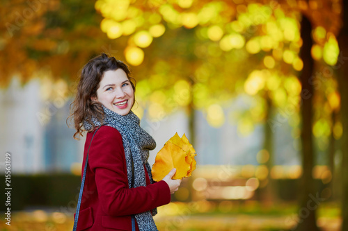 Girl in autumn park with golden foliage on a sunny fall day  holding yellow leaves in her hands