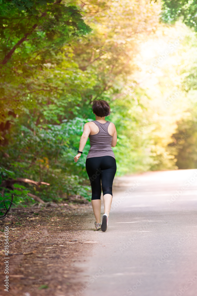 Woman running on a park road, outdoors jogging Woman running on a park road, outdoors jogging