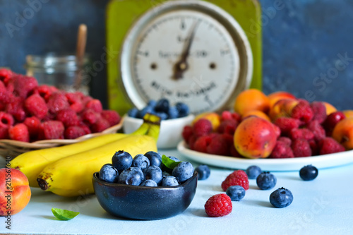 Set of berries and fruits on a blue background with rustic scales. Organic food.