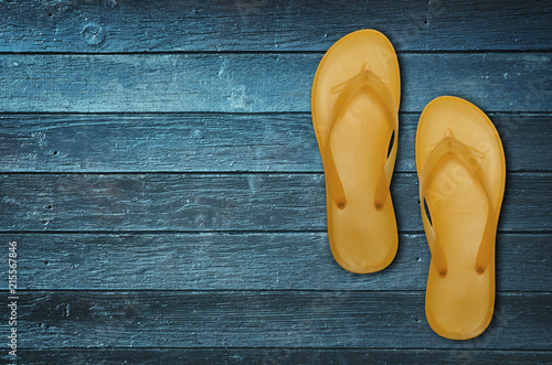 Bright flip-flops on blue wooden background
