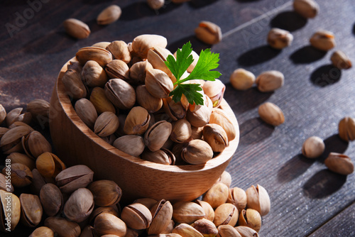 Composition with bowl of pistachio on wooden table. Delicacies