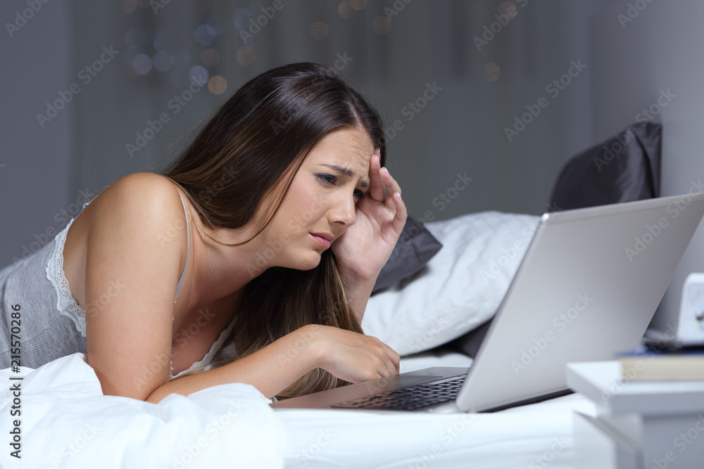 Worried woman reading bad news online in the night Worried woman reading bad news online in the night