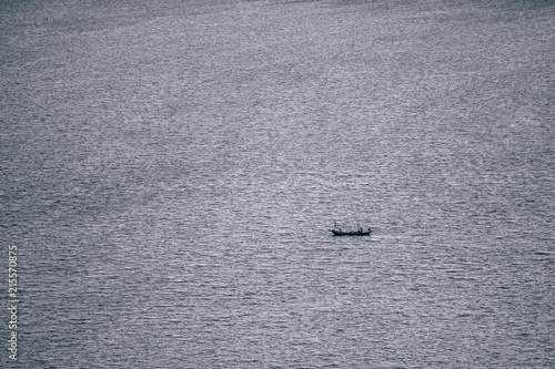 Small longtail boat alone in the sea floating towards its destination. Calm sea water with the longtail boat. © Igor