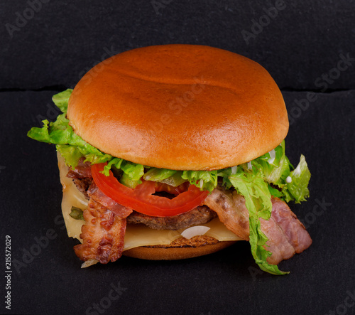 Fresh tasty burger, on black stone background.